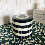 Black and white striped cylindrical stool on a patterned floor.