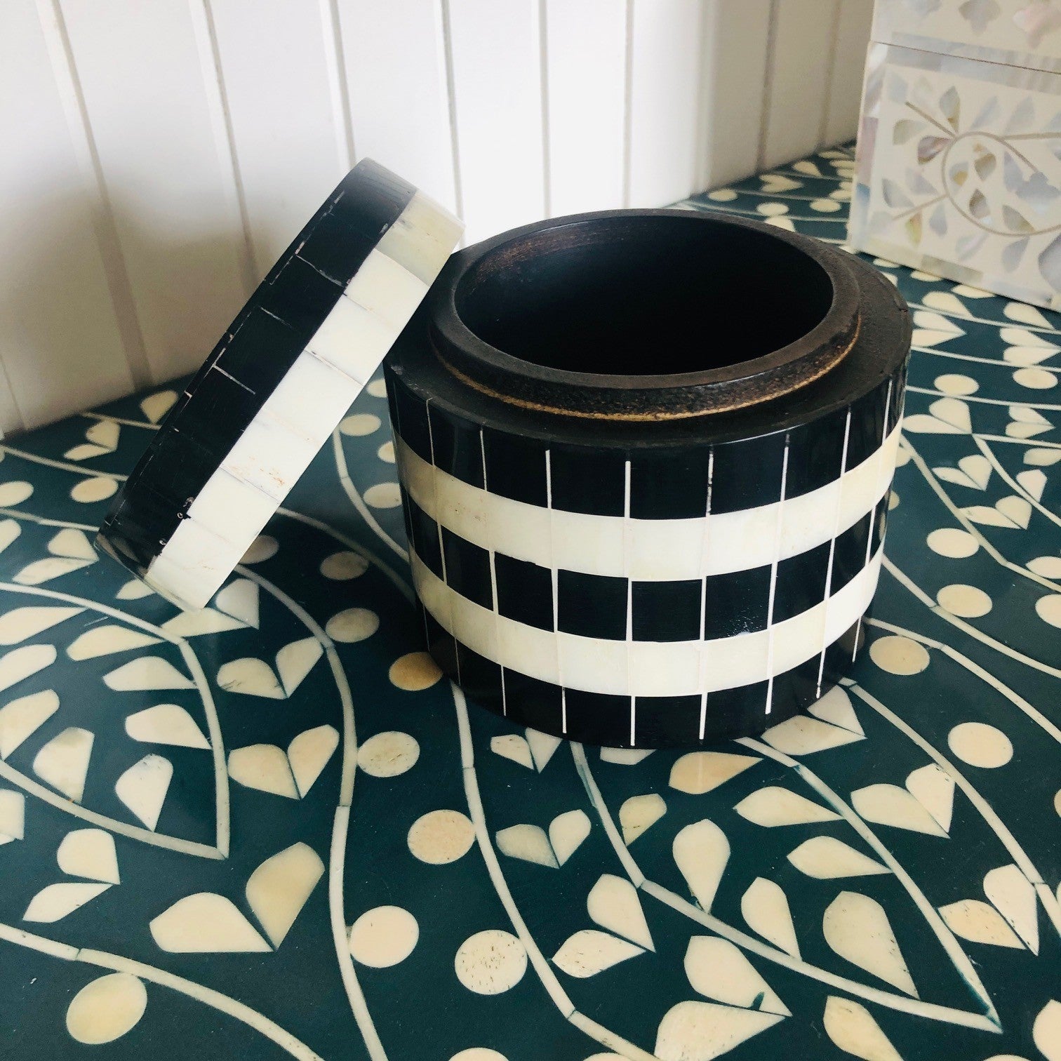 Black and white striped container on a patterned surface