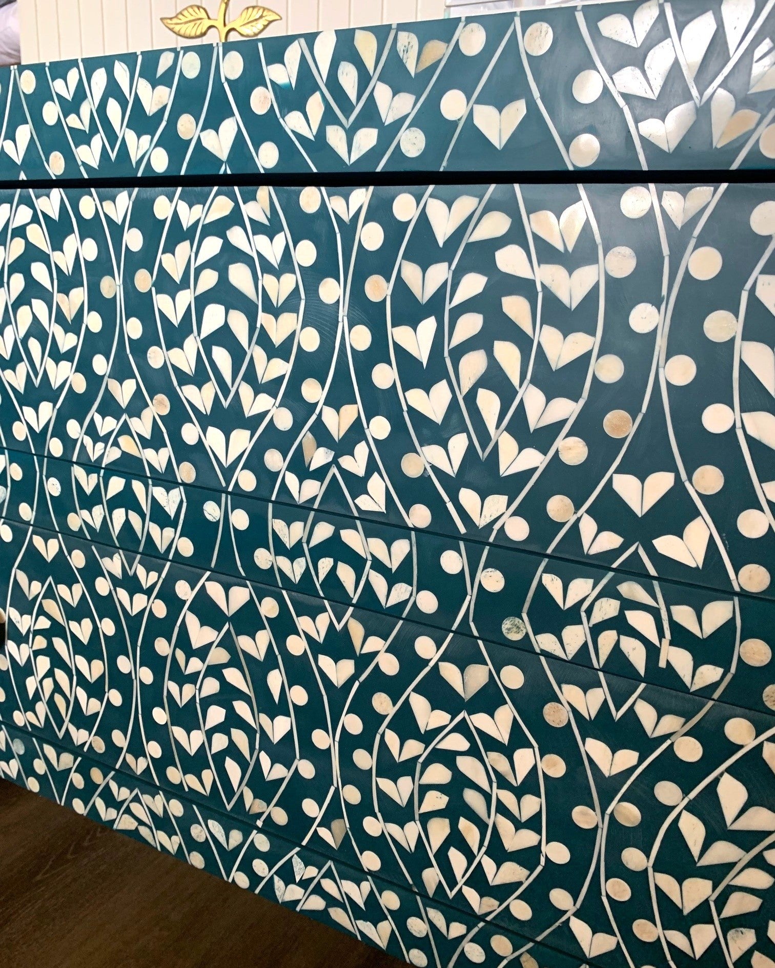 Teal fabric with white floral pattern on a wooden surface