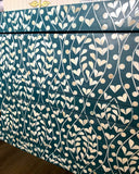 Teal fabric with white floral pattern on a wooden surface