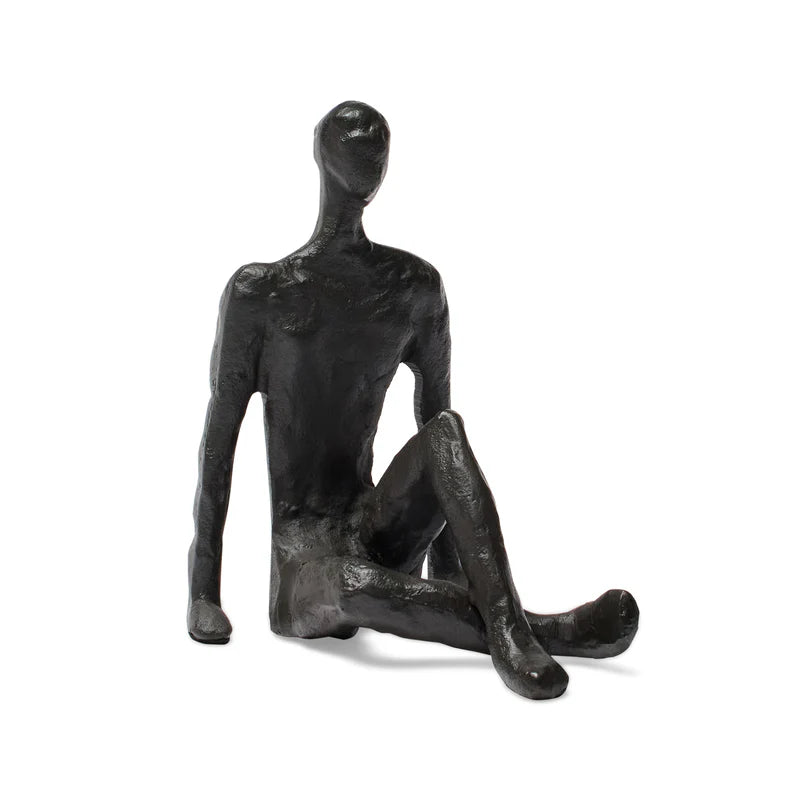 Black abstract sculpture of a seated figure on a white background
