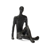 Black abstract sculpture of a seated figure on a white background