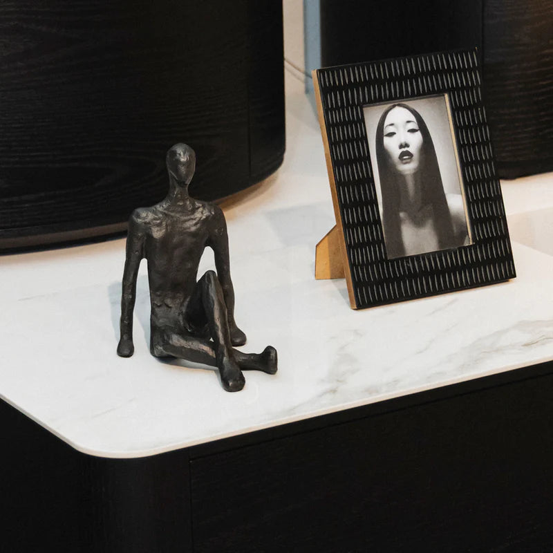 Black abstract sculpture on a marble surface with a framed photo of a woman.