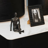 Black abstract sculpture on a marble surface with a framed photo of a woman.