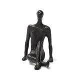Abstract black sculpture of a seated figure on a white background