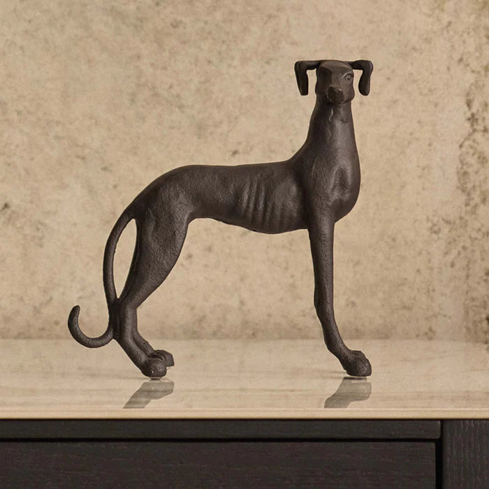 Bronze sculpture of a dog on a wooden surface with a beige background