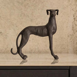 Bronze sculpture of a dog on a wooden surface with a beige background