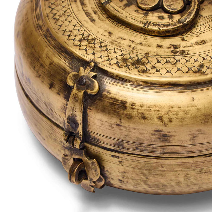 Close-up of an ornate gold box with intricate designs and a handle.