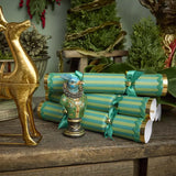 Decorative Christmas crackers with gold and green ribbons on a wooden table with festive decorations.