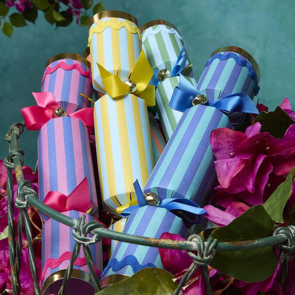 Colorful striped crackers with ribbons on a decorative stand surrounded by flowers.