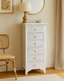 White patterned chest of drawers with a lamp and decorative items in a room setting.