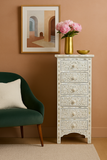 Decorative chest of drawers with floral arrangement against a brown wall