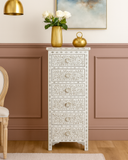 Decorative white chest of drawers with floral patterns against a pink wall.