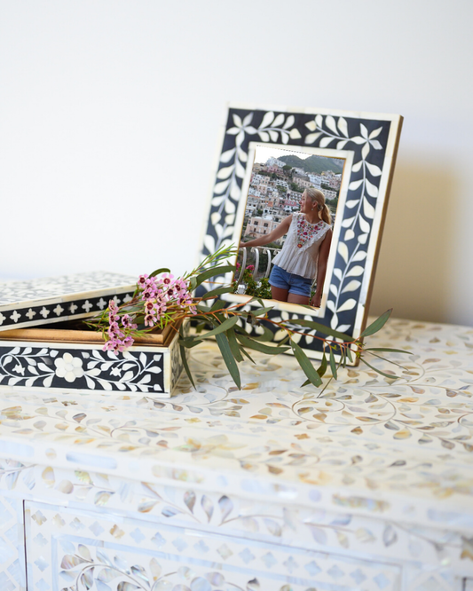 Decorative table with a floral arrangement, photo frame, and jewelry box.
