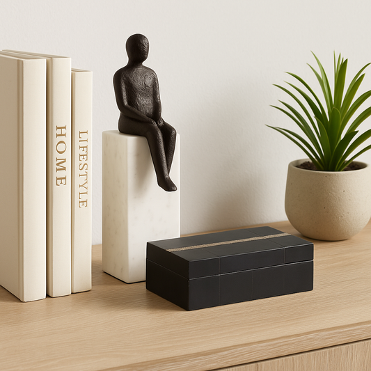Decorative setup with books, a statue, and a plant on a wooden surface.