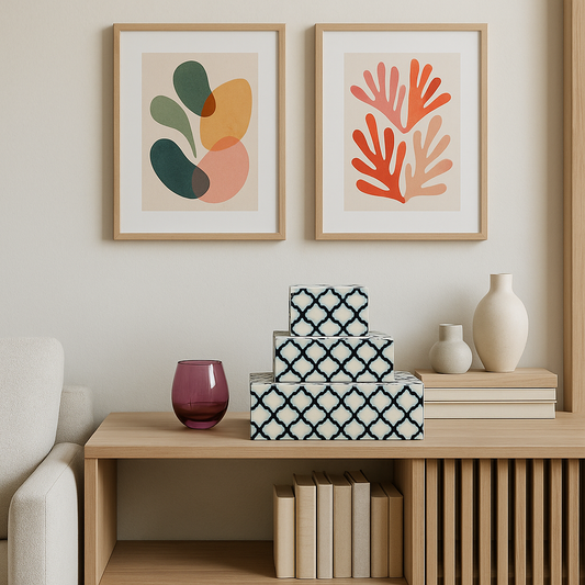 Decorative setup with framed abstract art, storage boxes, books, and a vase on a wooden shelf.