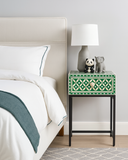 Green nightstand with decorative items next to a bed in a bedroom setting