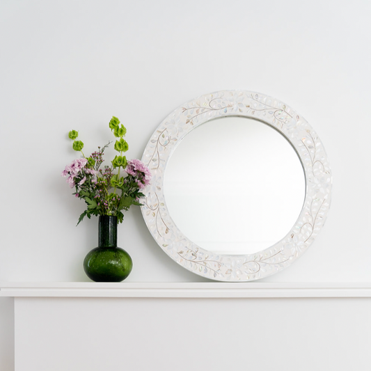 Decorative mirror with floral arrangement on a white surface