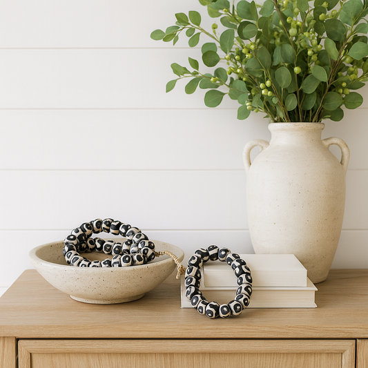 Decorative items including a vase with greenery, a bowl with a black and white patterned object, and a book on a wooden surface.