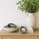 Decorative items including a vase with greenery, a bowl with a black and white patterned object, and a book on a wooden surface.