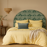 Bedroom with a decorative headboard, yellow bedding, and a side table with a plant.