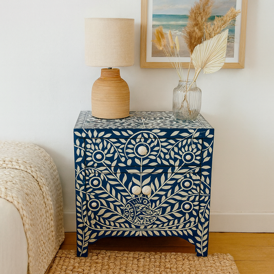 Decorative side table with floral pattern, lamp, and vase in a room setting.