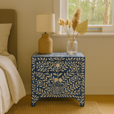 Decorative nightstand with floral patterns next to a bed in a bedroom.