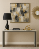 Modern interior with a console table, black lamp, Louis Vuitton book, and decorative items against a beige wall with abstract art.