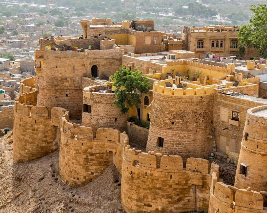 Large sand-colored fort with multiple towers and walls, set against a cityscape.