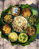 Platter of various Indian dishes on a large leaf with a wooden background