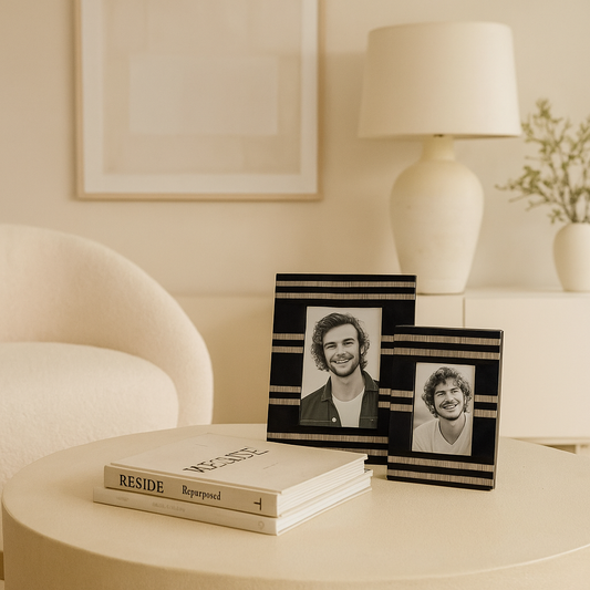Two framed photos on a table with a book titled 'Reside' in a cozy room setting.