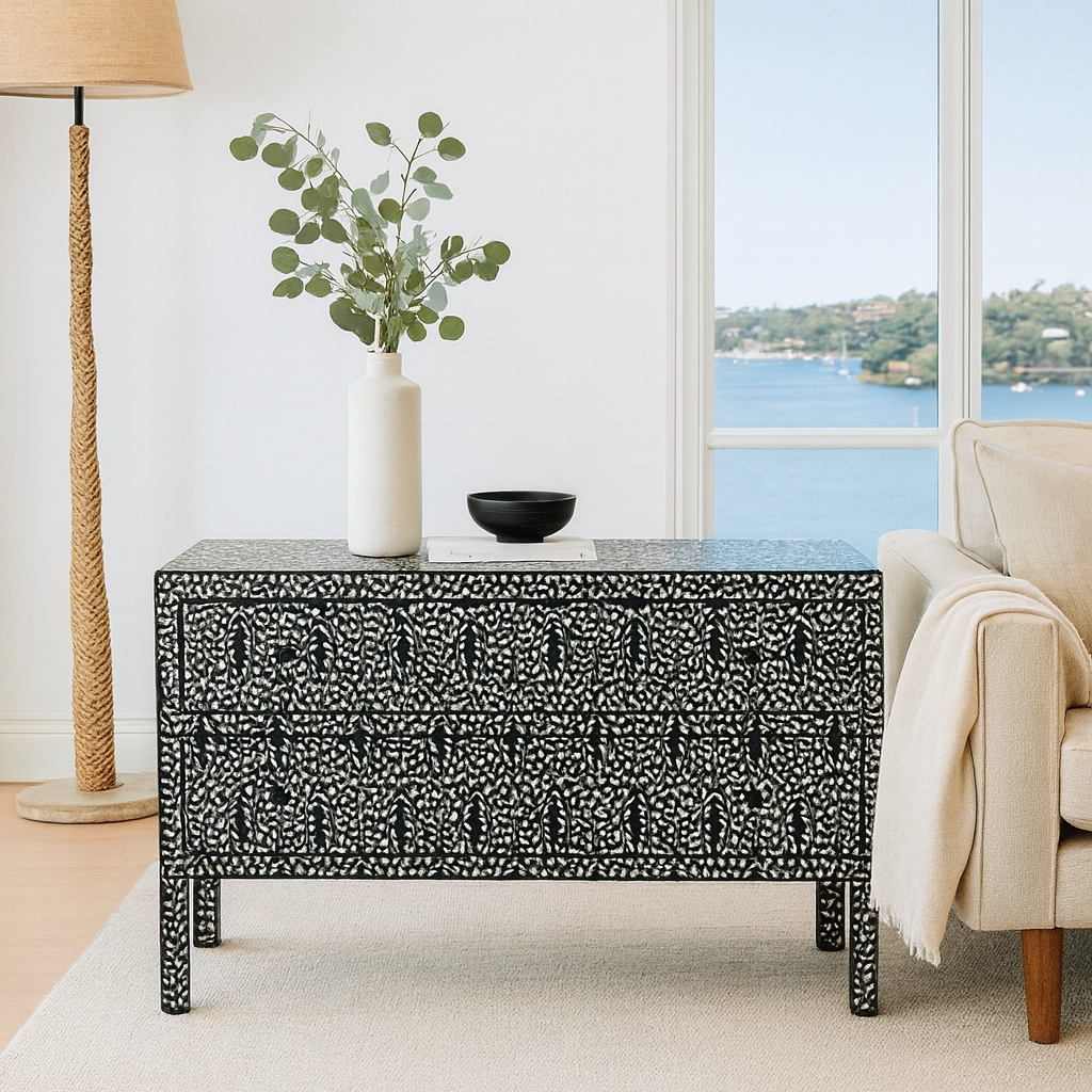 Decorative black and white patterned coffee table in a living room with a vase and plant.
