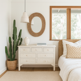Modern bedroom with a dresser, mirror, and bed with decorative pillows.