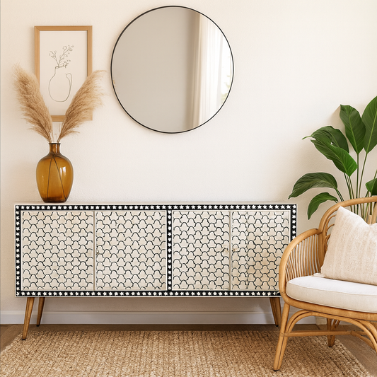 Decorative sideboard with a round mirror, vase, and plant in a room setting.