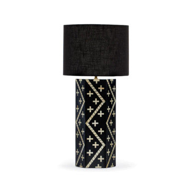 A black and white geometric patterned table lamp with a cylindrical shape and a black drum shade.