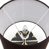 Close-up of a lamp with a black base, white shade, and visible light bulb.