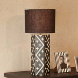 Decorative table lamp with a patterned base on a wooden surface.
