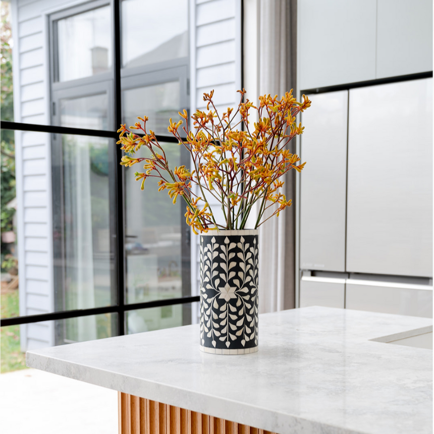 Decorative vase with yellow flowers on a white countertop in a modern kitchen.