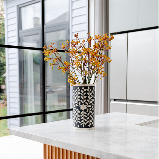 Decorative vase with yellow flowers on a white countertop in a modern kitchen.