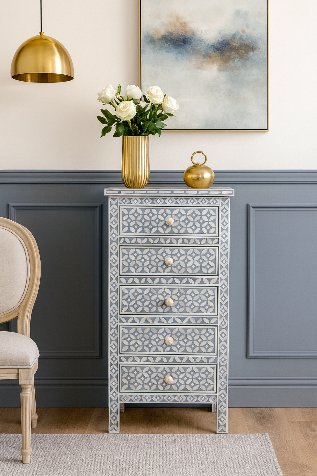 Decorative chest of drawers with floral arrangement and gold accents in a room with gray paneling.