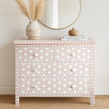 Decorative chest of drawers with floral patterns in a room with a wooden floor and white walls.
