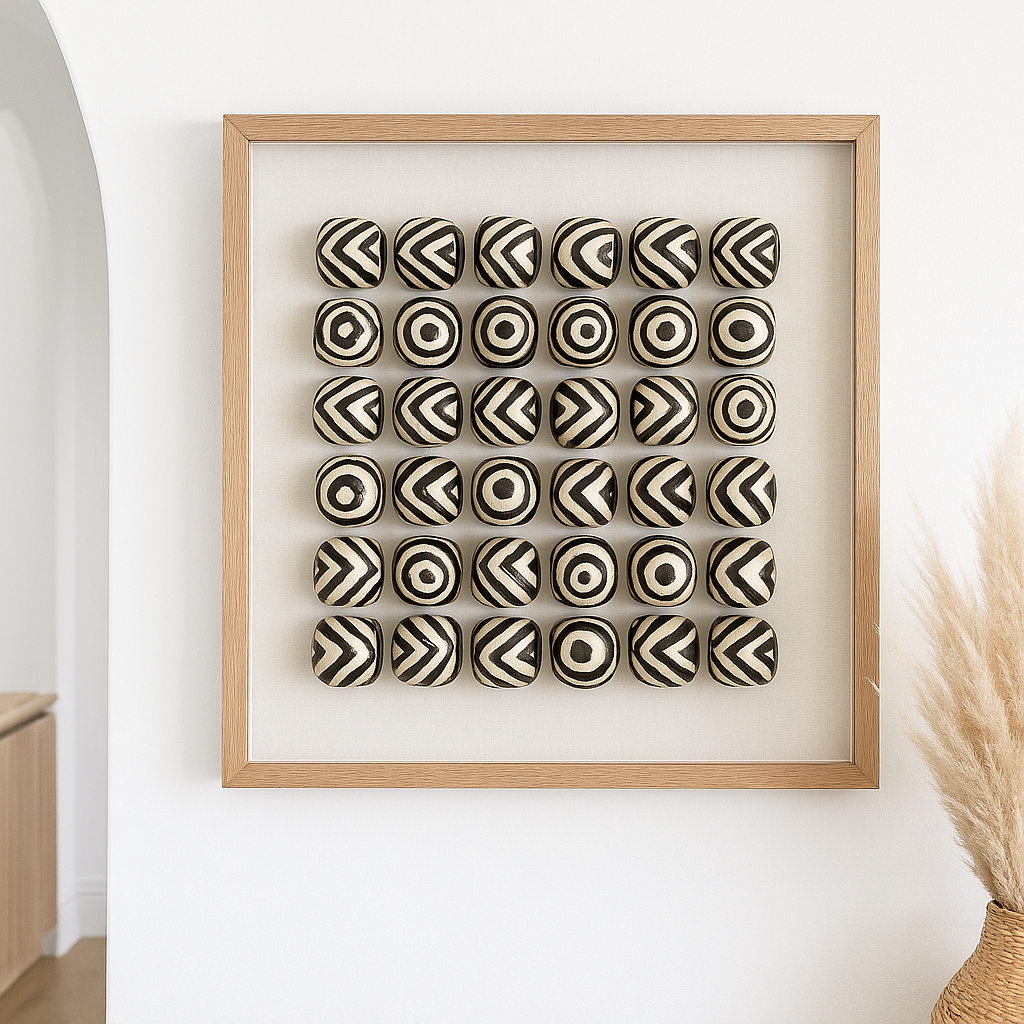 Framed artwork with black and white patterned balls on a white wall.