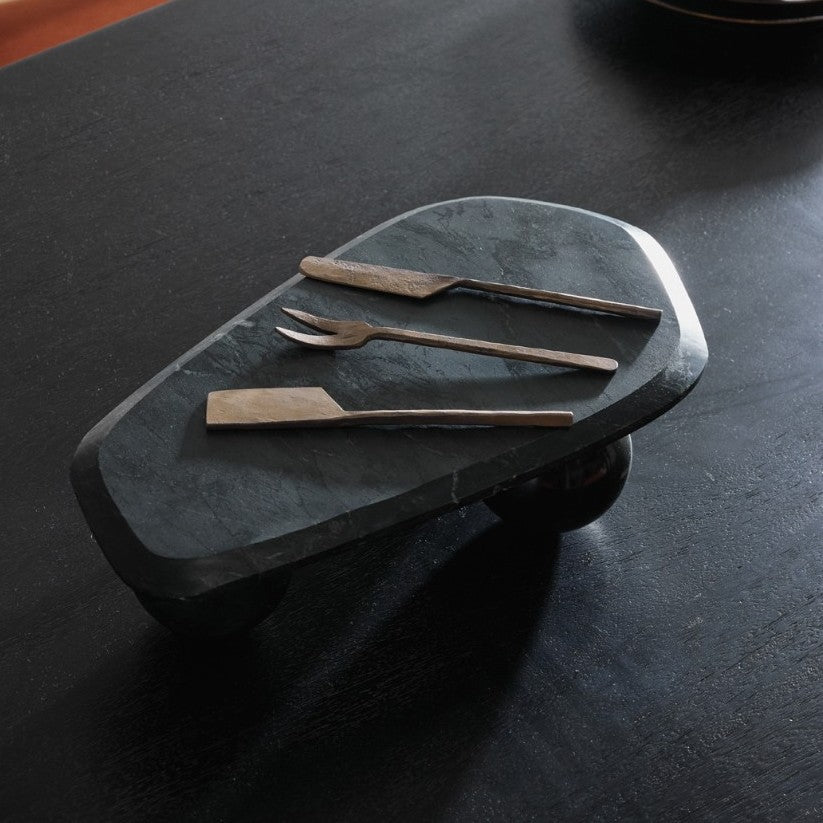 Set of metal utensils on a dark stone surface