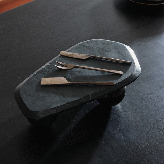 Set of metal utensils on a dark stone surface