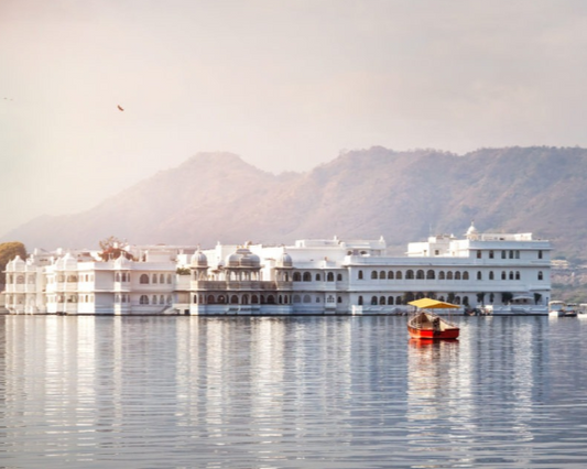 Lake Palace hotel on Lake Pichola with a boat and mountains in the background