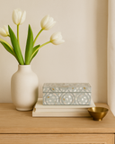 White tulips in a vase on a wooden surface with decorative box and gold bowl.