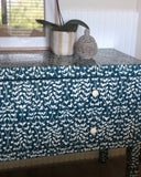 Teal and white patterned tablecloth on a table with decorative items.