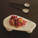 Marble tray with grapes on a dark surface